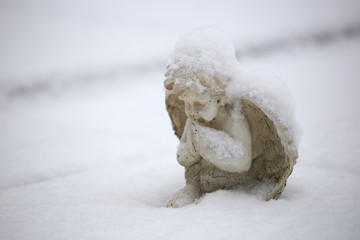 statue of small angel in snow at municipal cemetery in Amsterdam, The Netherlands