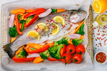 Fresh raw fish trout (wild salmon) with vegetables (broccoli, tomatoes, carrots, onions, Bulgarian...