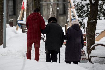 young man cares about the old mans. winter. Park