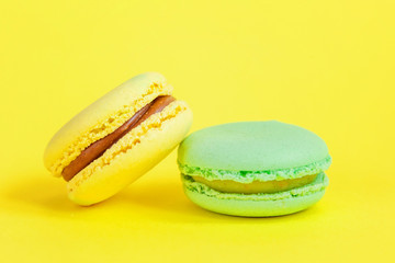 Sweet almond colorful unicorn blue yellow macaron or macaroon dessert cake isolated on trendy yellow modern fashion background. French sweet cookie. Minimal food bakery concept. Copy space