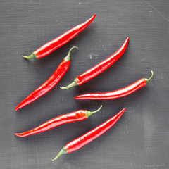 Hot red chili peppers on black surface, overhead. From above, top view, flat lay. Close-up.