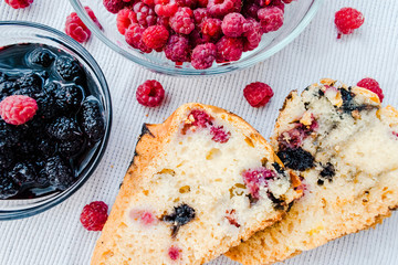 Piece of homemade simple pie with fresh red raspberries and black mulberry on a light background. Summer berry dessert. Flat lay. Food concept