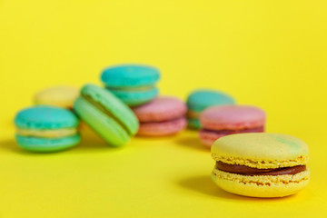 Sweet almond colorful unicorn pink blue yellow green macaron or macaroon dessert cake isolated on trendy yellow modern fashion background. French sweet cookie. Minimal food bakery concept. Copy space