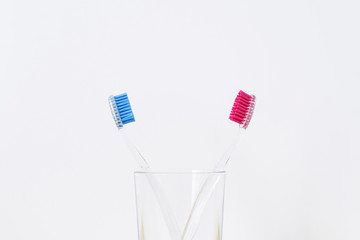 A glass with two plastic toothbrushes on white background. Love concept. Valentines day. Stomatology concept.