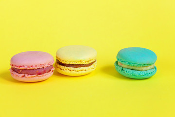 Sweet almond colorful unicorn pink blue yellow green macaron or macaroon dessert cake isolated on trendy yellow modern fashion background. French sweet cookie. Minimal food bakery concept. Copy space