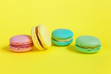 Fototapeta na wymiar Sweet almond colorful unicorn pink blue yellow green macaron or macaroon dessert cake isolated on trendy yellow modern fashion background. French sweet cookie. Minimal food bakery concept. Copy space