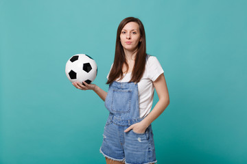 Beautiful young woman football fan support favorite team holding soccer ball isolated on blue...