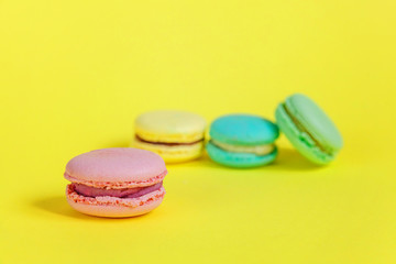 Sweet almond colorful unicorn pink blue yellow green macaron or macaroon dessert cake isolated on trendy yellow modern fashion background. French sweet cookie. Minimal food bakery concept. Copy space