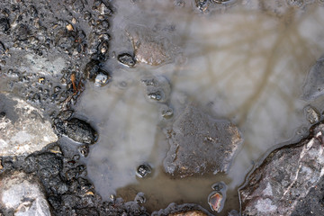 Asphalt crack fracture with old cobblestone and puddle surface texture