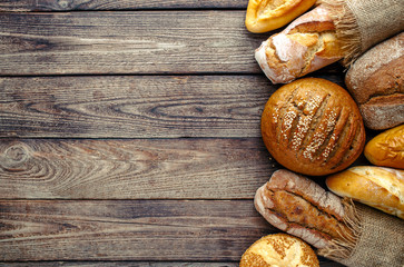 Assortment of baked bread on wooden table background,top view