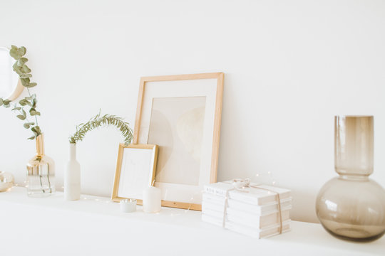 White table with photo frame, gift box, vase, eucalyptus at white wall. Modern interior design concept.
