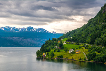 Fototapeta na wymiar Amazing nature view with dramatic sky and wooden houses on the banks of the Norwegian fjord. Scandinavian Mountains, Norway. Artistic picture. Beauty world.