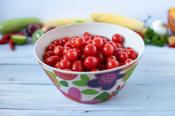 Cherry tomatoes in bamboo bowl on a wooden table.
