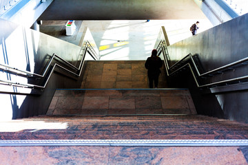 People walking on stairs. Steps leading to the basement. Marble stairs from several levels. Metal gelenders next to the stairs