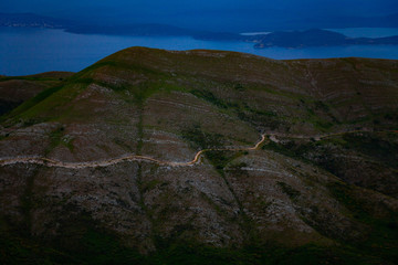 Fototapeta premium Aerial view of beautiful green mountain with road on it. Nature concept with scenic view of hill with blue sky