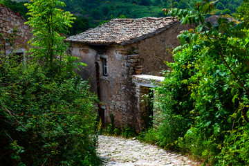Fototapeta na wymiar Old stone house by the village stone road. Nature and village concept with old retro stone buildings and roads