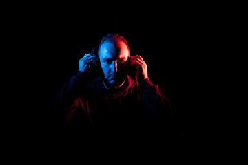 DJ Taking his Headphones Off or On in a Dark Room .Red and Blue light on Face.
