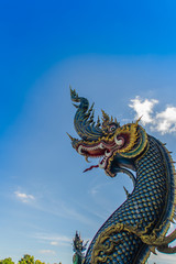 Fototapeta na wymiar Beautiful blue naga sculpture with blue sky and white cloud on the sunny day at the public temple, Wat Rong Sua Ten, Chiang Rai, Thailand. Naga is a very great snake, found in the Buddhism temples.