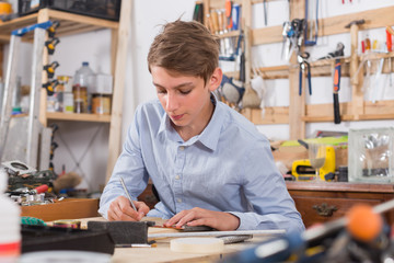 teenager  smiling and working with wood in the workshop