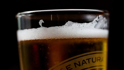 Poured beer in a glass with dark background. Alcohol beverage in the glass