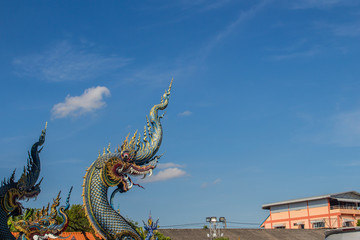 Fototapeta premium Beautiful blue naga sculpture with blue sky and white cloud on the sunny day at the public temple, Wat Rong Sua Ten, Chiang Rai, Thailand. Naga is a very great snake, found in the Buddhism temples.