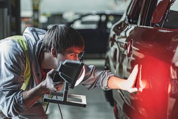 An employee of the car body painting shop checks the quality