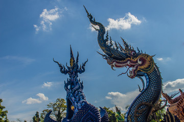 Fototapeta na wymiar Beautiful blue naga sculpture with blue sky and white cloud on the sunny day at the public temple, Wat Rong Sua Ten, Chiang Rai, Thailand. Naga is a very great snake, found in the Buddhism temples.