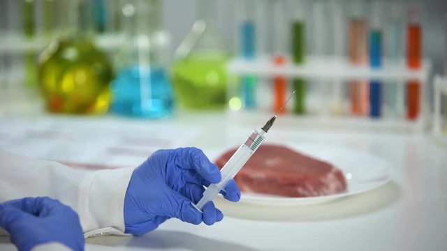 Scientist injecting liquid in meat sample conducting product quality analysis