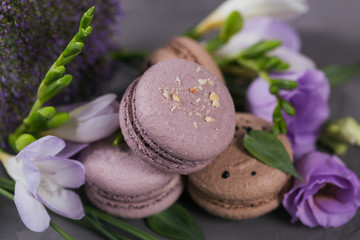 Obraz na płótnie Canvas Heap of sweet french macarons mixed with flowers on grey concrete background