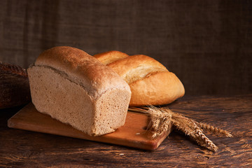 Different bread and wheat on the rustic table. Selective focus, close up