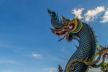 Beautiful blue naga sculpture with blue sky and white cloud on the sunny day at the public temple,...