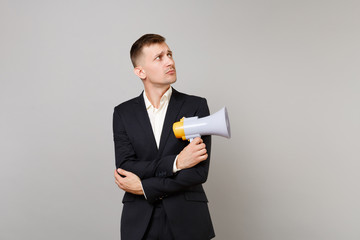 Young business man in classic black suit shirt looking aside holding hands with megaphone crossed...