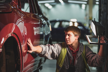 An employee of the car body painting shop checks the quality