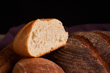 Bakery - gold rustic crusty loaves of bread and buns on black chalkboard background. Still life captured from above