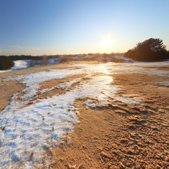 winter sunset sun on the horizon / sand desert snow lying on the sand