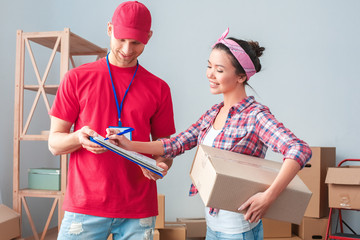 Young girl moving to new place standing with delivery man fulfilling form happy