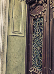 Glass wooden of a building on the street door with an iron decorative ornament. Old Tbilisi architecture