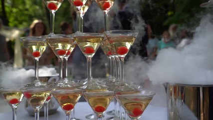 Moscow / Russia - 09 01 2018: A slide of glasses with alcoholic cocktails stands on a white tablecloth, near the visible clouds of dry smoke a man's hand takes one of the glasses, 