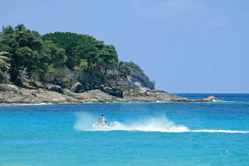 Fototapeta na wymiar lagoon with clear blue water, tropical greenery and rocks with water bike