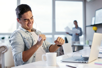 Happy businessman listening music over earphones while working in the office.