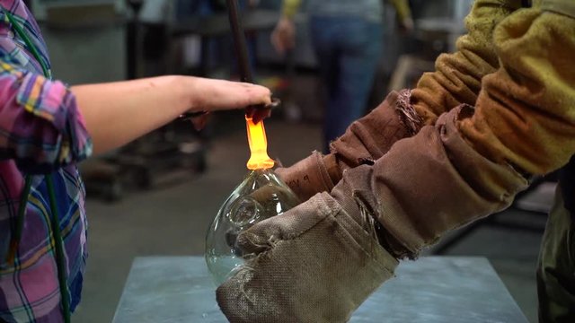 Glass blowers making a beautiful piece of glass art together