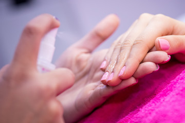 Obraz na płótnie Canvas Women's hands on pink towel in nail salon