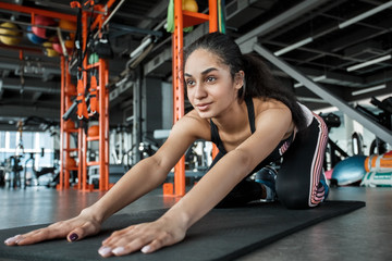 Young woman in gym sporty lifestyle on mat stretching back happy close-up