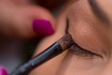 Make-up artist puts eye liner on woman's eye in the salon