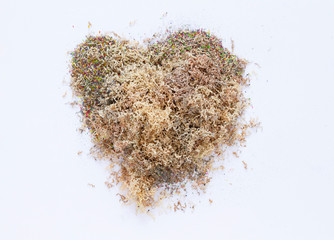 Heap of colour dust from pencils in heart-shaped on white background