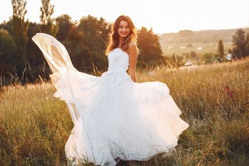 Fototapeta premium Beautiful bride walking in a summer field