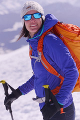 randonnée en raquette portrait de femme au sac à dos orange fluo et des lunettes de soleil fashion