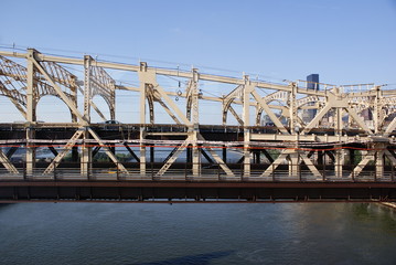 Front view of one side of the Queensboro Bridge at noon with transit of vehicles leaving
