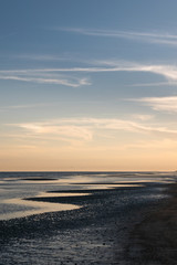 Vertical shot of ssea shore with wavy patterns in the sand at dusk