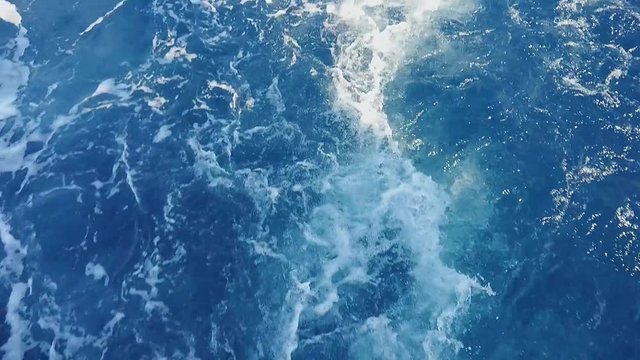 White bubble powerful waves pushed out by moving boat motor propeller, large stream of blue water with white foam rising up. Mobile smart phone footage.